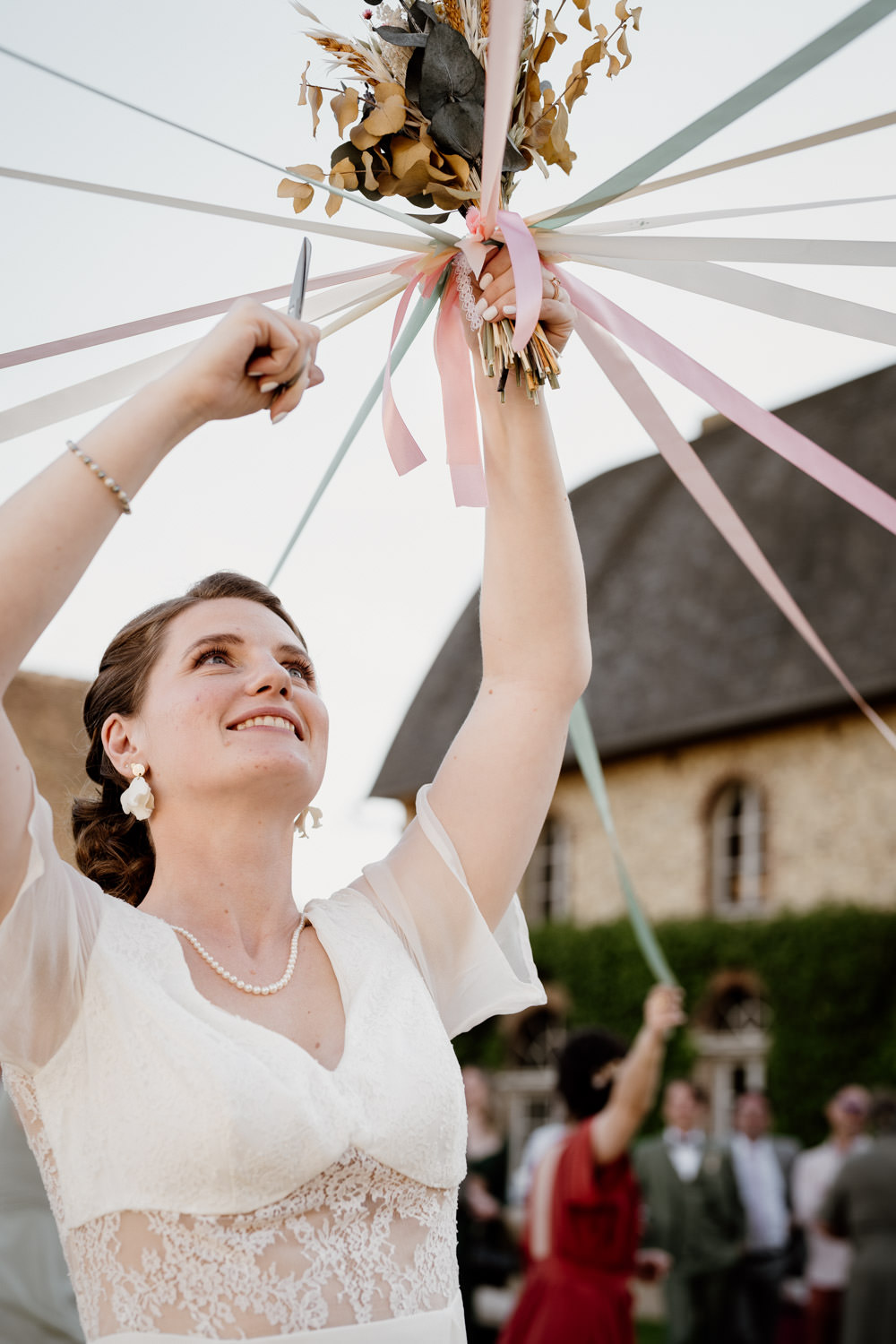 Mariée s'apprêtant à couper les rubans entourant son bouquet pour le jeu du ruban